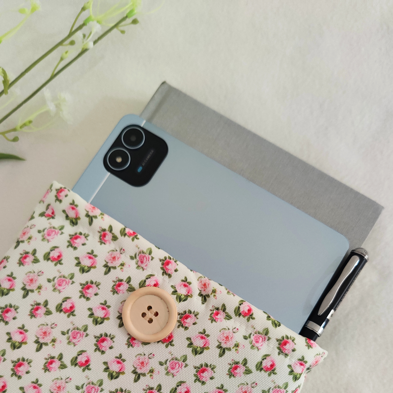 Floral book sleeve holding a book and a smartphone, highlighting its versatile storage.